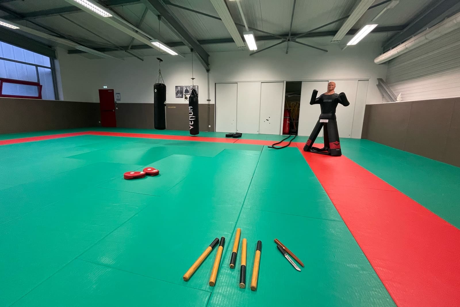 Le tatami du Kobukaï à Séné équipé pour la self-défense : sac de frappe, mannequin d’entraînement, bâtons et couteaux d’entraînement
